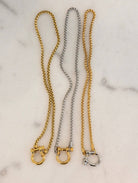 Three gold and silver chain collars on a marble surface