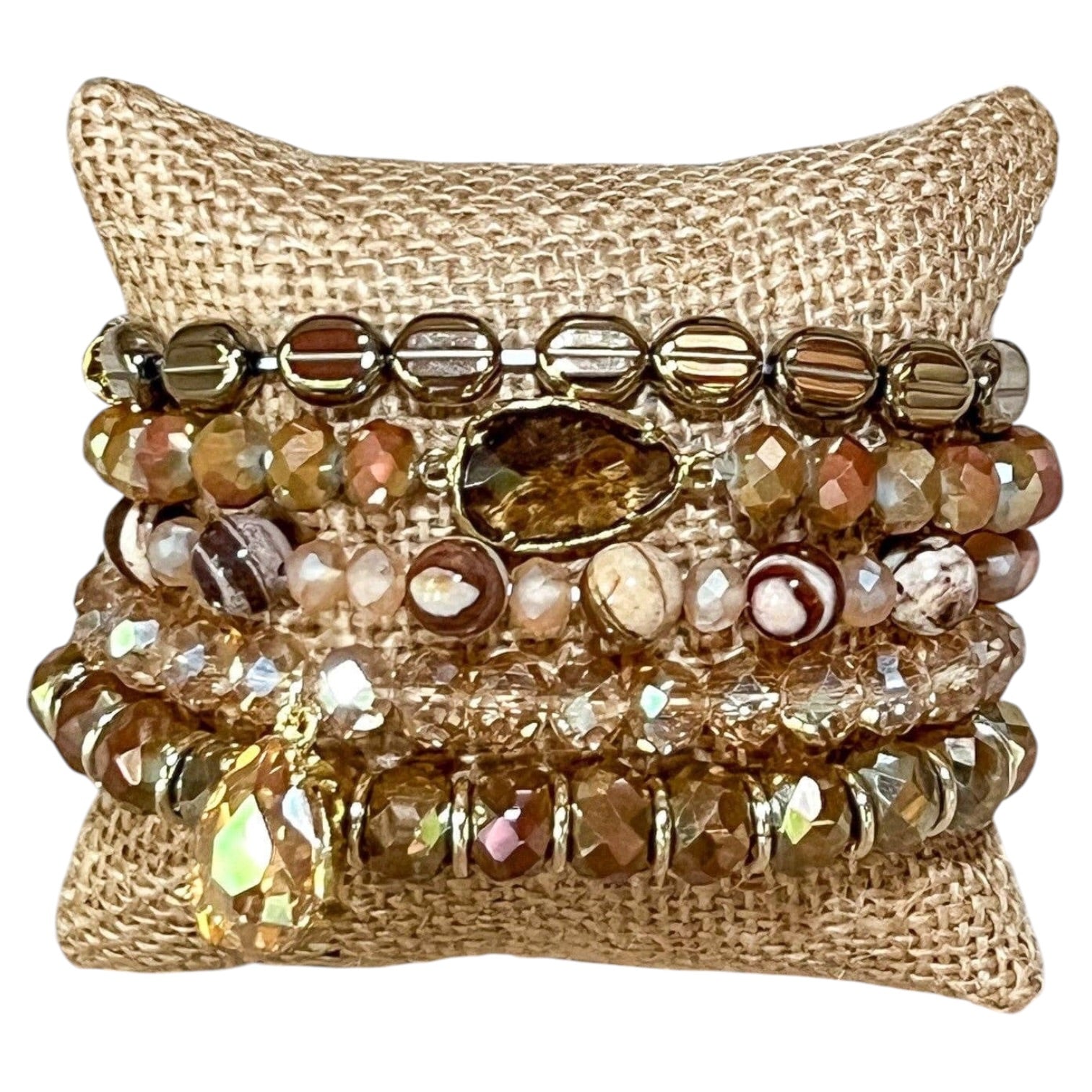 Stack of beaded bracelets on a textured beige pillow