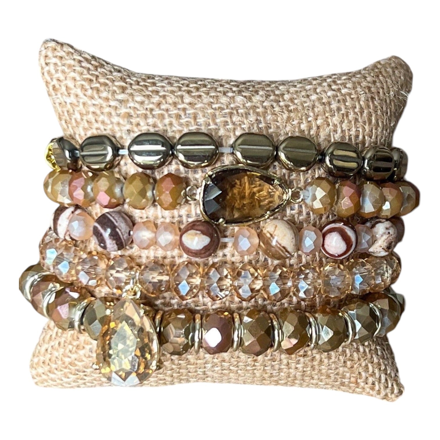 Stack of beaded bracelets on a textured beige pillow