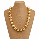 Gold necklace on a brown mannequin bust with a white background