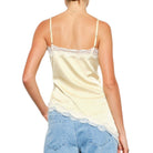 woman wearing yellow satin cami with white lace on white background