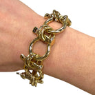 Gold chain bracelet on a wrist with a plain background