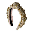 Decorative headband with beige textured band and gold embellishments on a white background