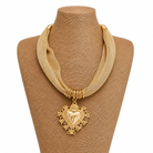Gold necklace with a heart pendant on a brown mannequin bust.