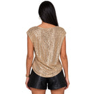 A woman shown from the back wearing a gold sequined cap-sleeve top and black faux-leather shorts against a plain white background.