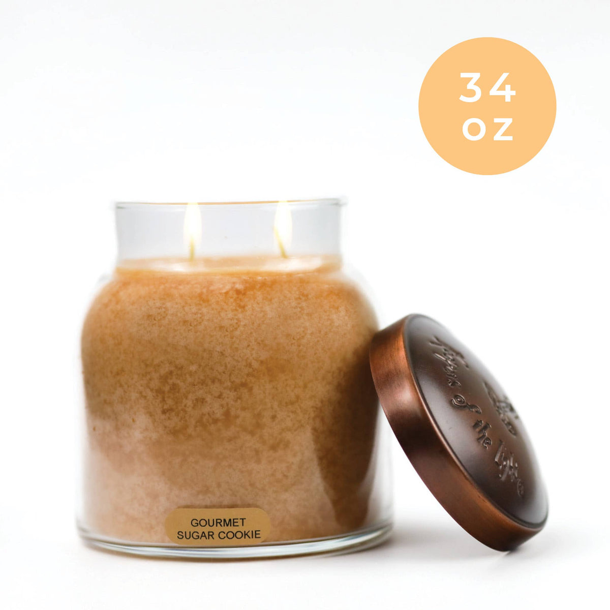 Gourmet sugar cookie-scented candle in a glass jar with a bronze lid on a white background