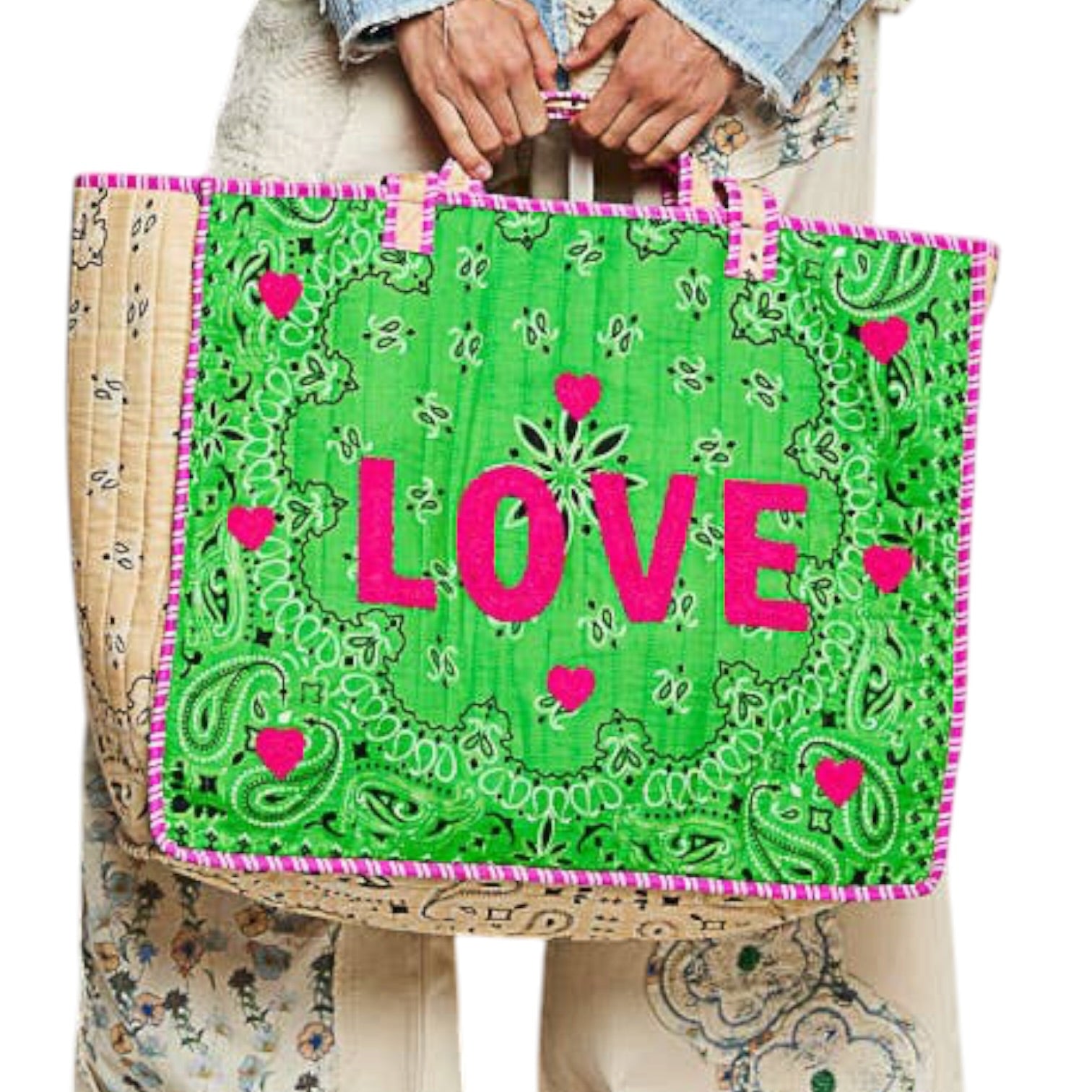 A person holds a large tote bag with a bright green paisley print, pink trim, and the word "LOVE" in bold pink letters across the front.