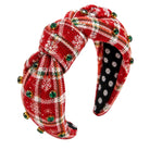 A festive red holiday plaid twisted fabric headband decorated with green and gold rhinestones and white snowflakes, shown on a plain white background.