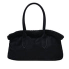 A black handbag with a soft, fuzzy shearling-style trim along the top edge and double top handles, shown against a plain white background.