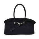 A black suede handbag with a black faux-fur trim, double top handles, and a decorative strap with gold-tone hardware, shown against a plain white background.