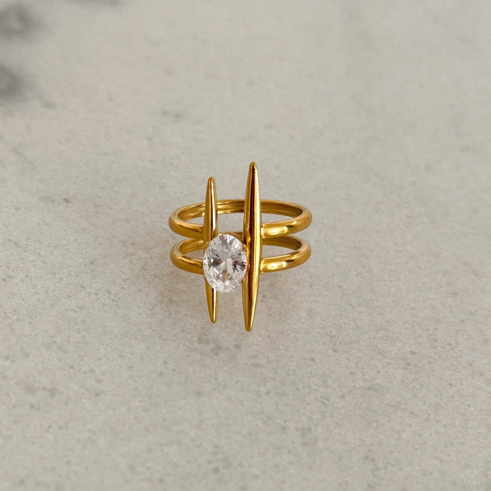 Gold ring with a central gemstone on a gray background