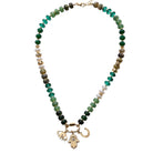Necklace with green and gold beads and a hamsa charm on a white background