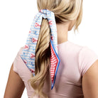 Person wearing a colorful hair scarf tied around their ponytail on a white background