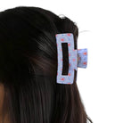 Hair clip with a patterned design on a person's hair against a white background