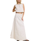 Woman wearing a white sleeveless top and long skirt on a white background