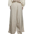 Striped pants worn with a light-colored top on a white background