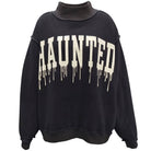 A black crewneck sweatshirt featuring the word 'HAUNTED' printed across the chest in a dripping white font, displayed on a clean white background.