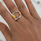 Silver and gold ring on a person's finger with a neutral background