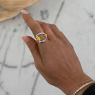 Hand wearing a ring with a gold & silver on a marble surface
