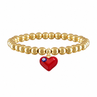 Gold beaded bracelet with a red heart charm on a white background