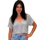 Woman wearing a gray crop top and blue jeans on a white background