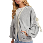 Woman wearing a gray hoodie with white trim on a white background