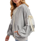 Gray hoodie with lace details on sleeves worn by a model on a white background