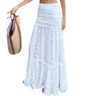 Woman wearing a light blue lace maxi skirt holding a straw bag on a white background
