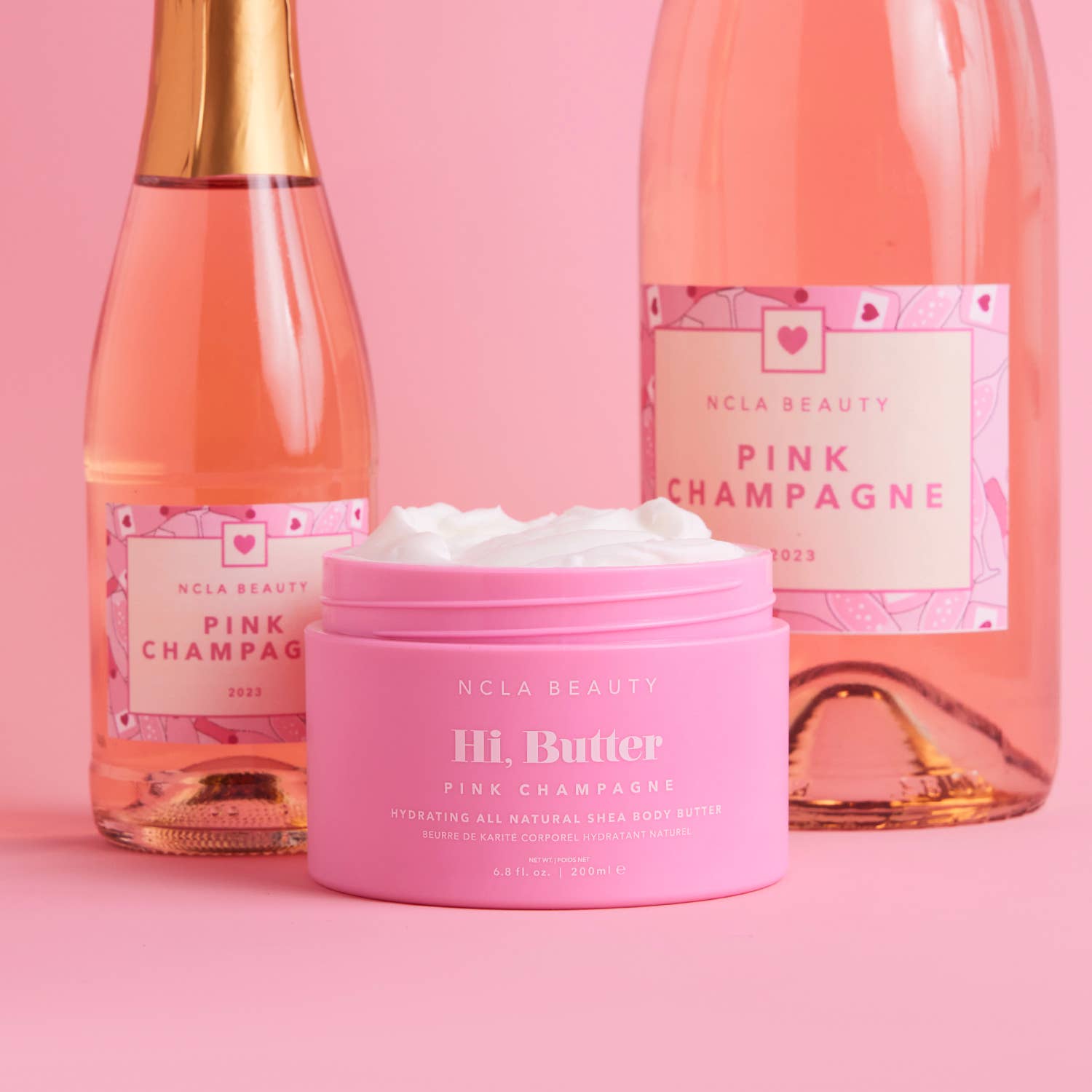 Pink Champagne-themed skincare products including a bottle, a jar, and a box on a pink background.