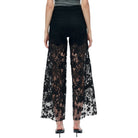Black lace pants worn by a person on a white background