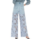 Light blue jeans with floral lace detailing on a white background