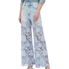 Light blue jeans with floral lace detailing on a white background