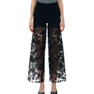 Black lace pants worn by a person on a white background