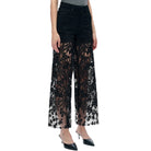 Black lace pants worn by a person on a white background