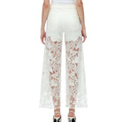 White lace pants worn by a person on a white background