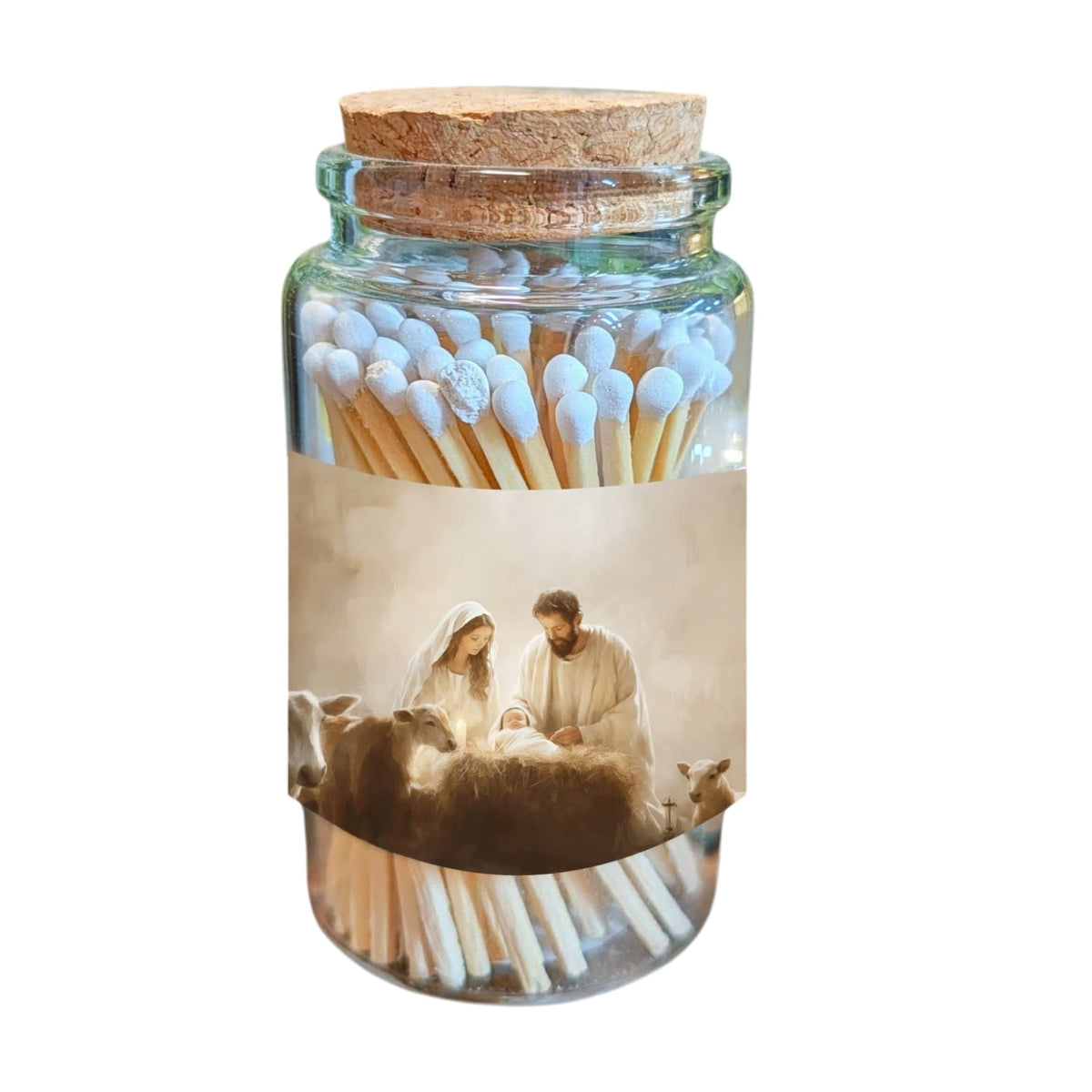 A clear glass jar with a cork stopper filled with wooden matchsticks, wrapped in a label showing a nativity scene with Mary, Joseph, and baby Jesus with sheep. The jar is photographed on a plain white background.