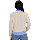 A woman shown from the back wearing a cream-colored ribbed knit cardigan over a light blue striped shirt and blue jeans, against a plain white background.