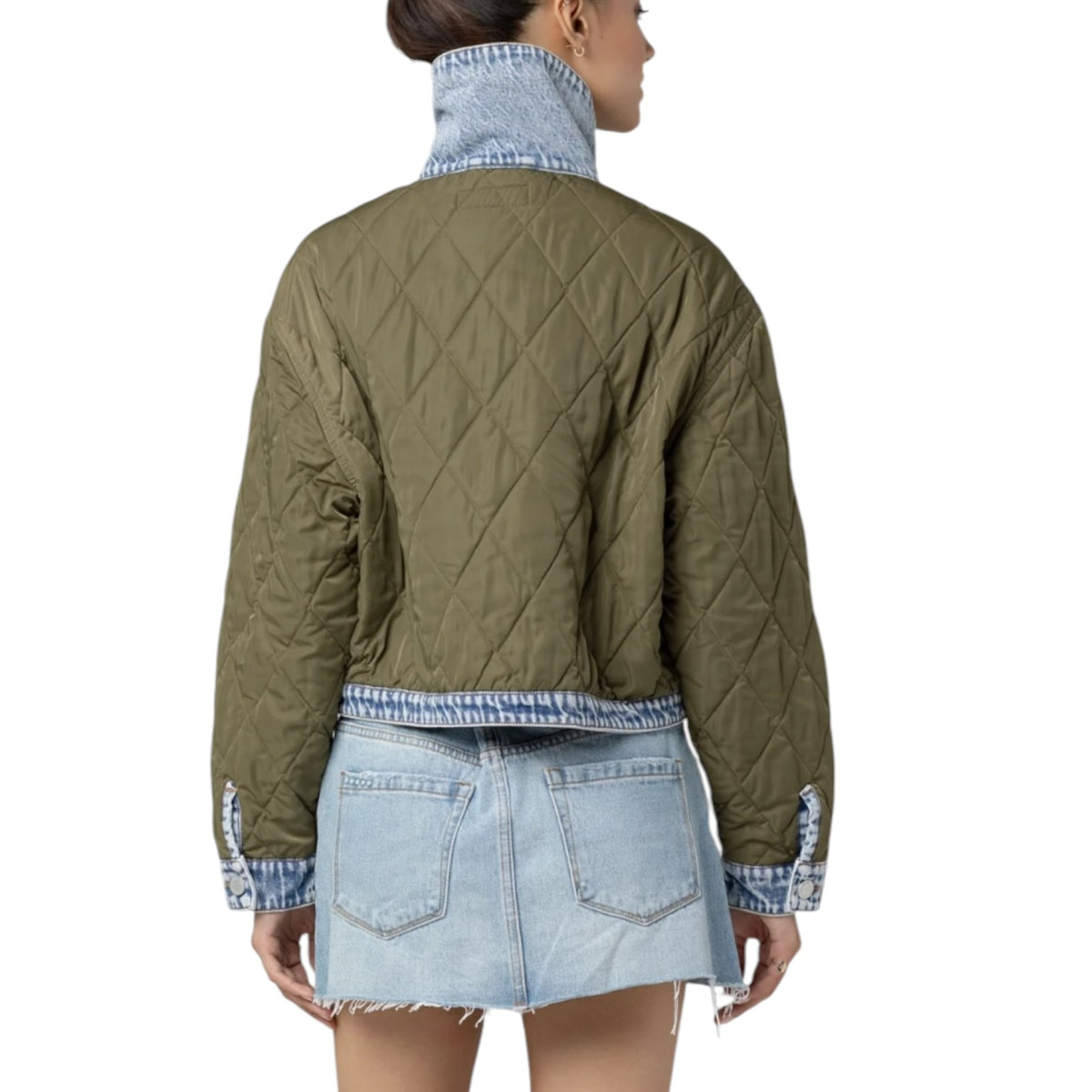 A model shown from the back wearing an olive green quilted jacket with a high-waisted light blue denim mini skirt and a matching denim mock neck collar.