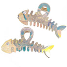 Two fishbone-shaped hair clips with iridescent finish on a white background