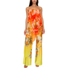 Woman wearing a strapless floral jumpsuit with orange and yellow flowers on a white background