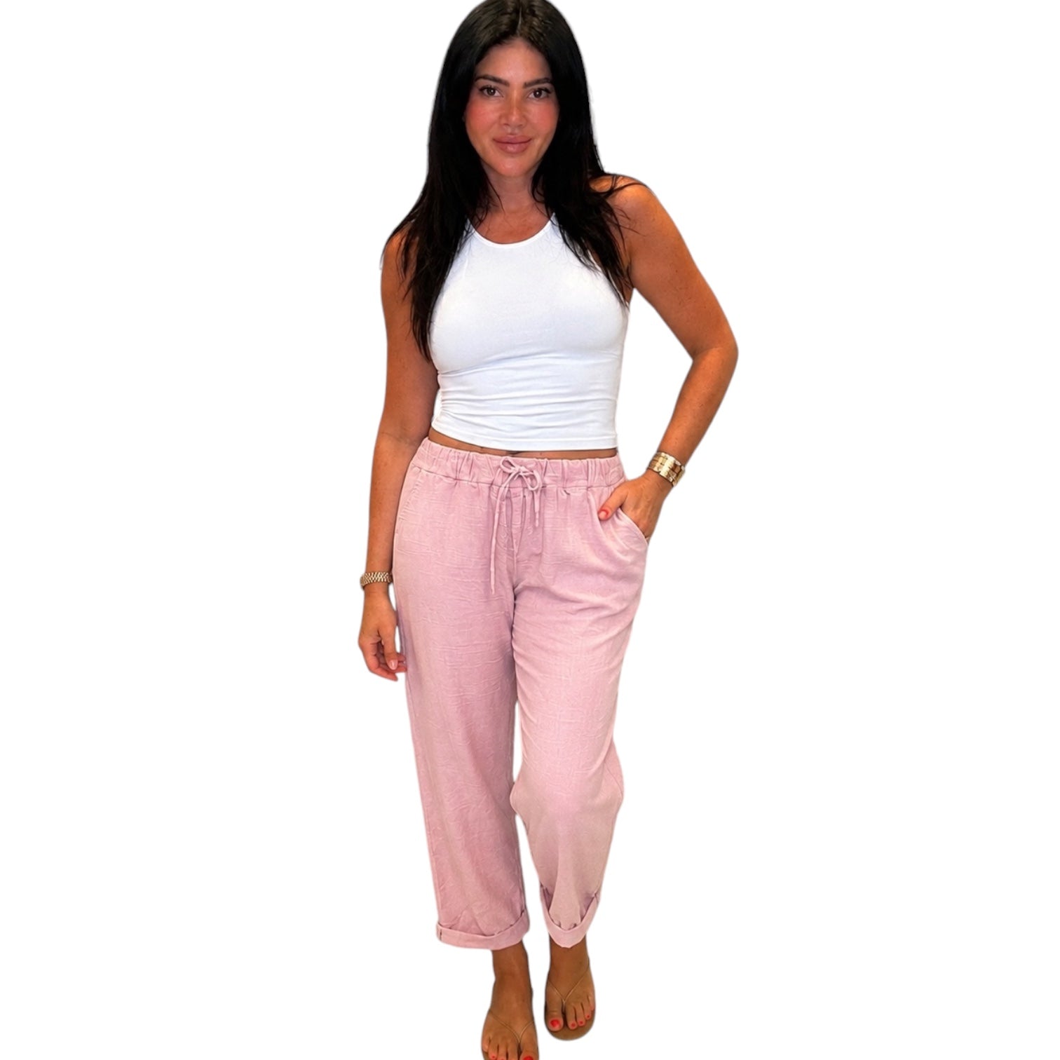 Woman wearing a white tank top and pink pants on a white background