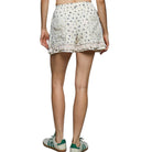 Person wearing floral shorts and green sneakers on a white background