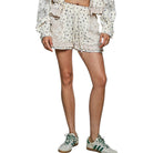 Person wearing floral shorts and green sneakers on a white background