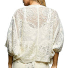 White lace top worn by a person on a white background