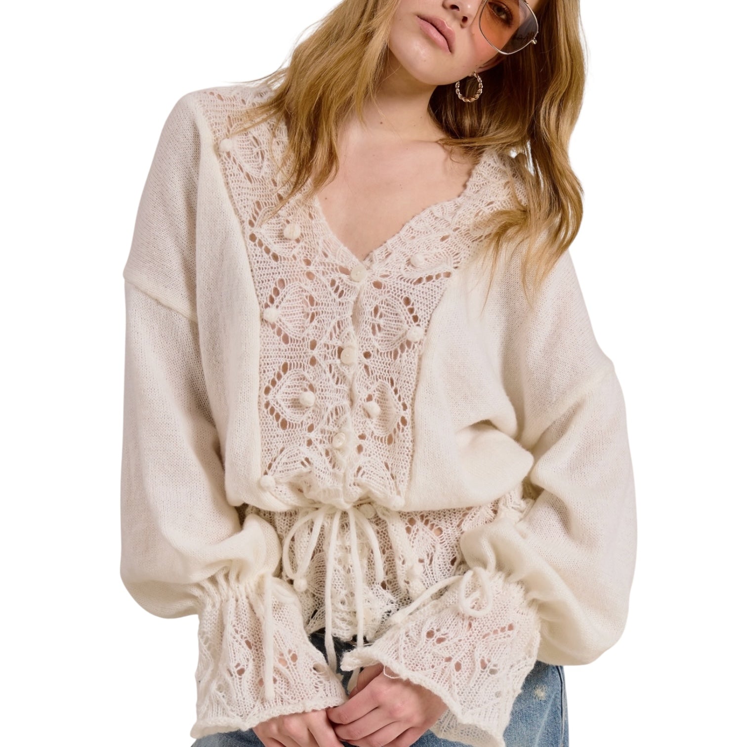 Woman wearing a cream-colored lace blouse with long sleeves on a white background