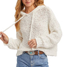 Woman wearing a cream knitted sweater and blue jeans on a white background