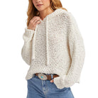 Woman wearing a chunky knit sweater and jeans on a white background