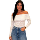 Woman wearing a white off-shoulder top with lace detailing and blue jeans on a white background