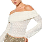 Woman wearing a white off-shoulder top with sheer sleeves on a white background