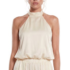 Woman wearing a beige halter neck top on a white background